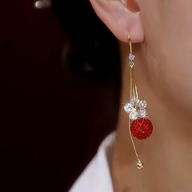 Model showcasing the dangle and style of the 14K Gold-Plated Zircon Flower Red Crystal Ball Ear Hook Earrings