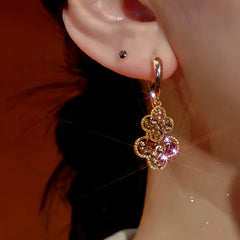 Model showcasing the dangle and style of the 14K Gold-Plated Zircon Four-Leaf Flower Earrings
