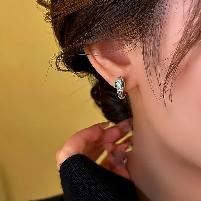 Model showcasing the dangle and style of the 14K Gold-Plated Zircon Green-Eyed Snake Hoop Earrings