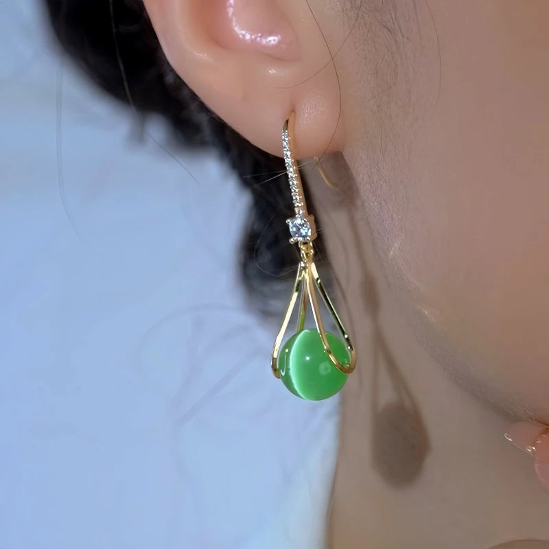 Model showcasing the dangle and style of the 14K Gold-Plated Zircon Green Cat's Eye Bead Ear Hooks