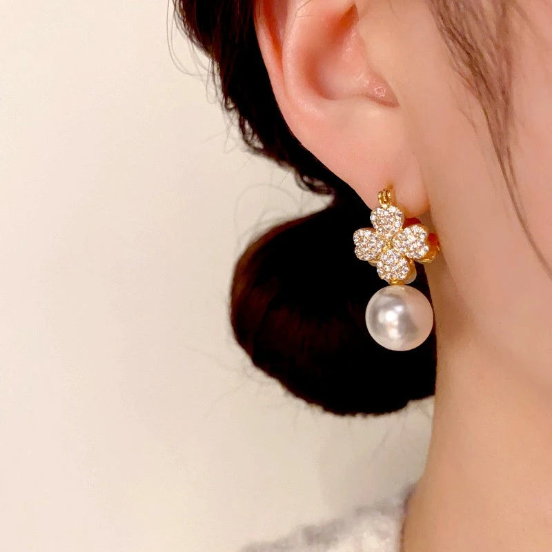 Model showcasing the dangle and style of the 14K Gold-Plated Zircon Green Cat's Eye Stone Flower Pearl Earrings