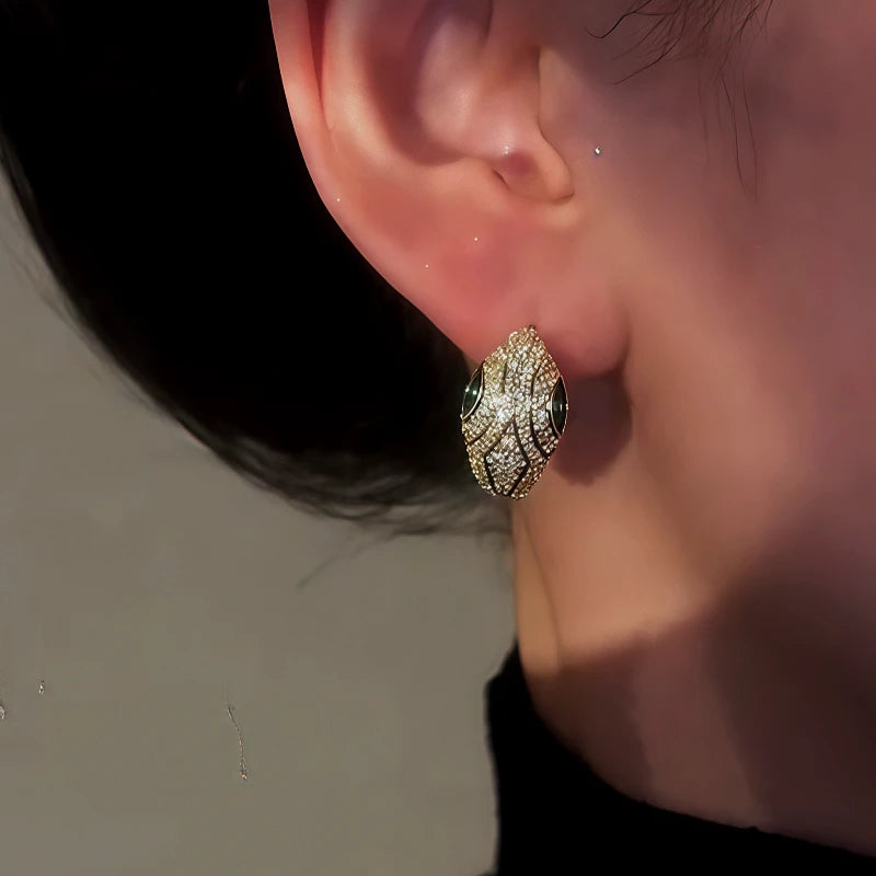 Model showcasing the dangle and style of the 14K Gold-Plated Zircon Green Eye Snake Hoop Earrings