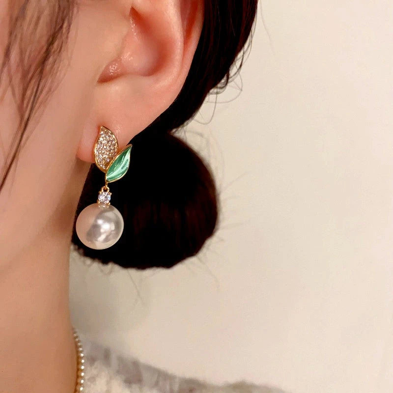 Model showcasing the dangle and style of the 14K Gold-Plated Zircon Green Leaf Pearl Earrings
