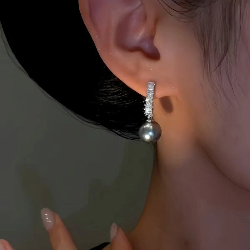Model showcasing the dangle and style of the 14K Gold-Plated Zircon Grey Pearl Earrings