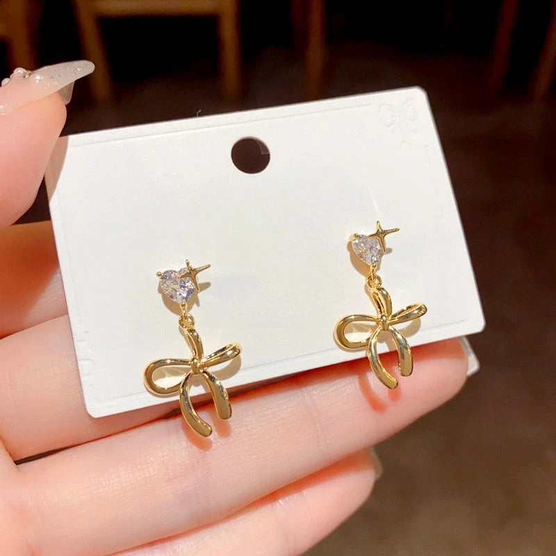 Model showcasing the dangle and style of the 14K Gold-Plated Zircon Heart Bow Tassel Earrings