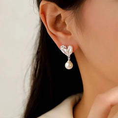 Model showcasing the dangle and style of the 14K Gold-Plated Zircon Heart Pearl Earrings