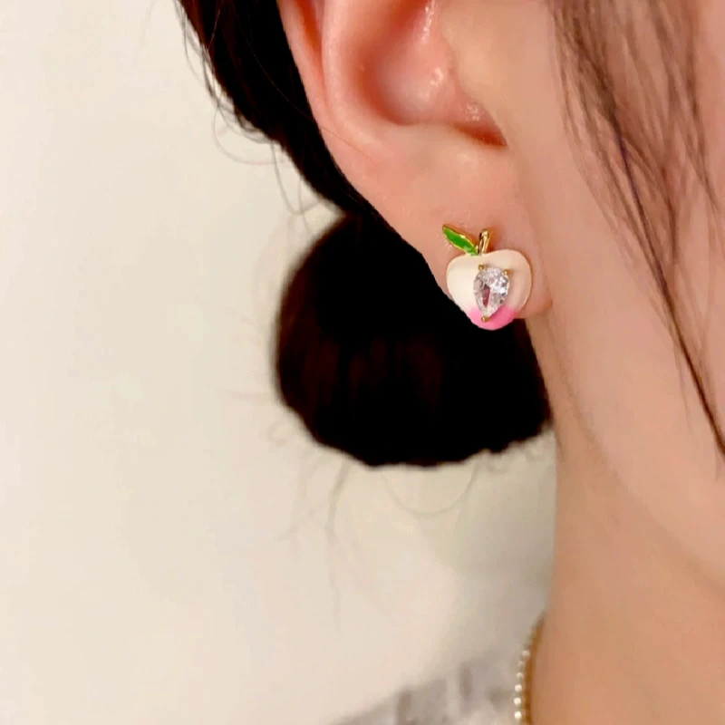 Model showcasing the dangle and style of the 14K Gold-Plated Zircon Oil Drop Peach Stud Earrings