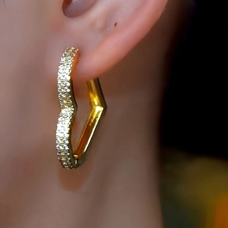 Model showcasing the dangle and style of the 14K Gold-Plated Zircon Peach Heart-Design Earrings