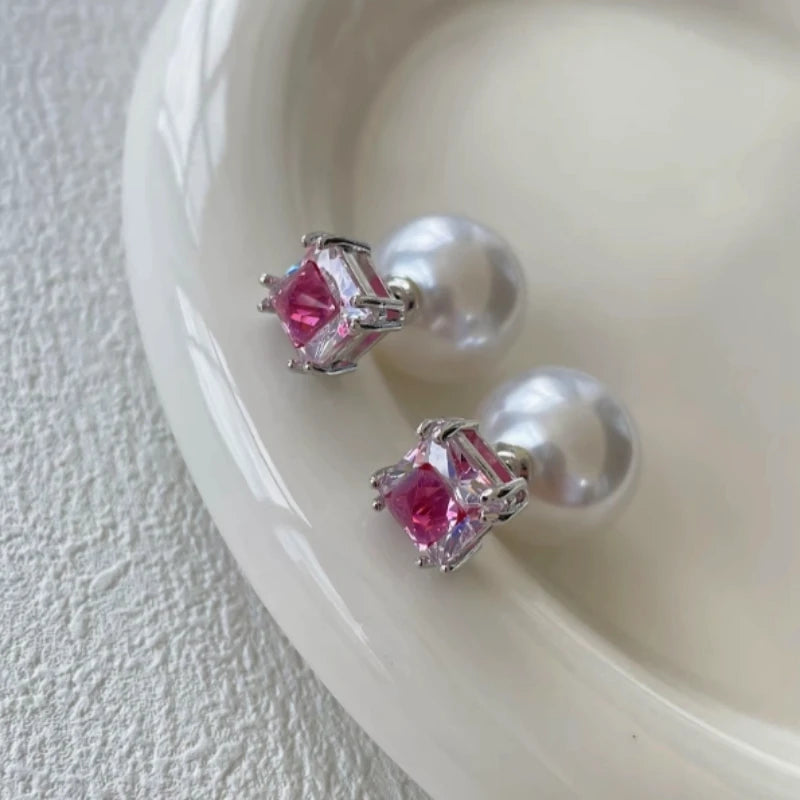 Pink square cubic zirconia pearl stud earrings on white ceramic dish