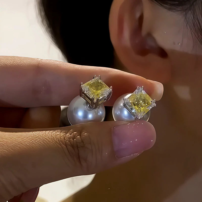 Yellow square CZ pearl stud earrings held by hand near ear