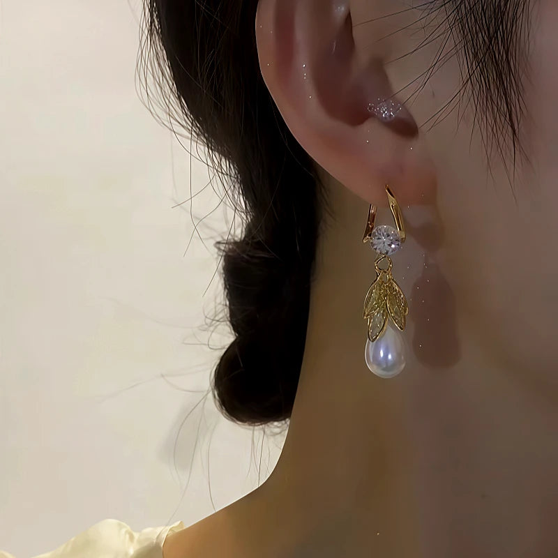 Side angle view of gold leaf teardrop pearl dangle earring worn on ear