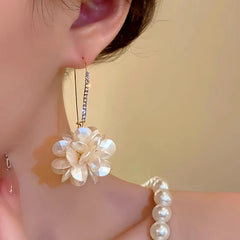 Close-up of pearlescent white floral drop earring on woman's ear