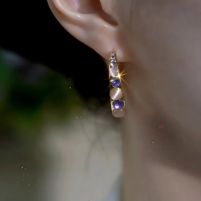 Side view of gold purple crystal opal half hoop earring worn on ear