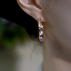 Side view of gold purple crystal opal half hoop earring worn on ear