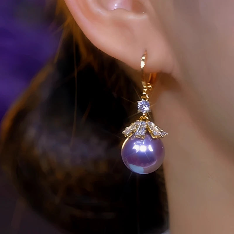 Model showcasing the dangle and style of the 14K Gold-Plated Zircon Purple Pearl Earrings