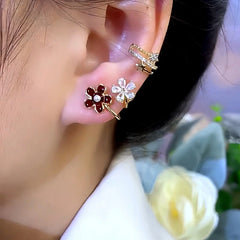 Matching dual-flower gold earring worn on ear with crystal star ear cuff, close up