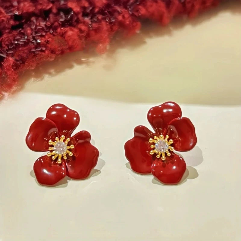 Angled view of the 14K Gold-Plated Zircon Red Glaze Flower Stud Earrings