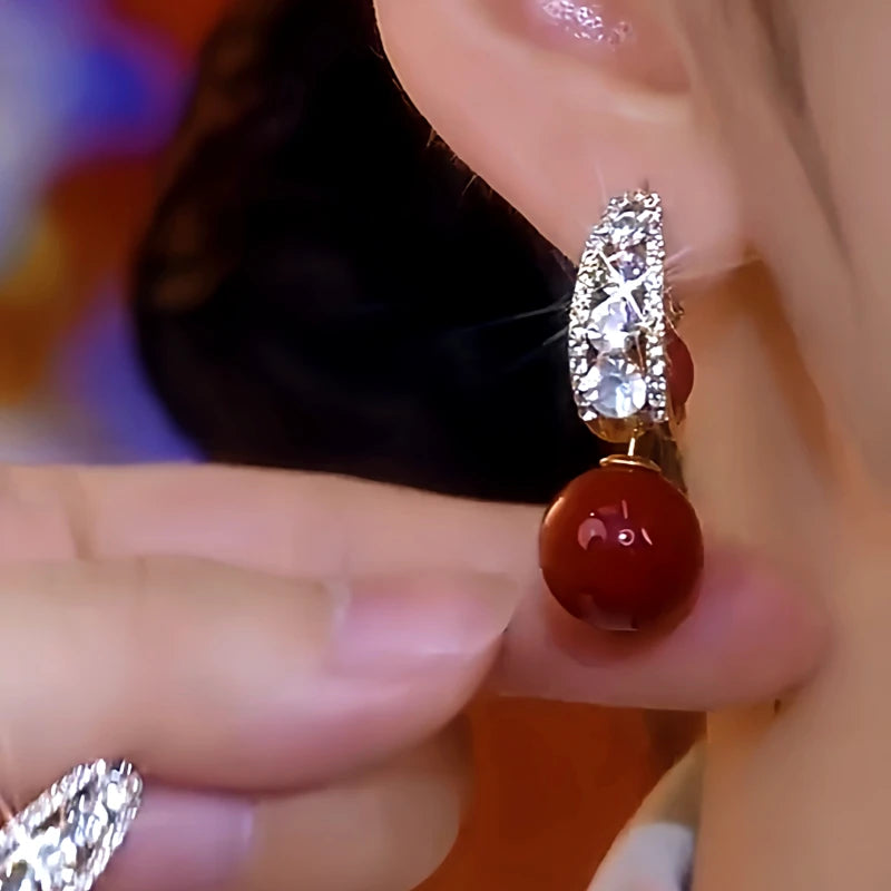 Model showcasing the dangle and style of the 14K Gold-Plated Zircon Red Pearl Earrings