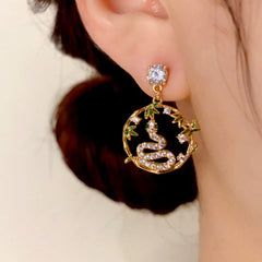 Close-up of gold bamboo snake CZ drop earring worn on ear