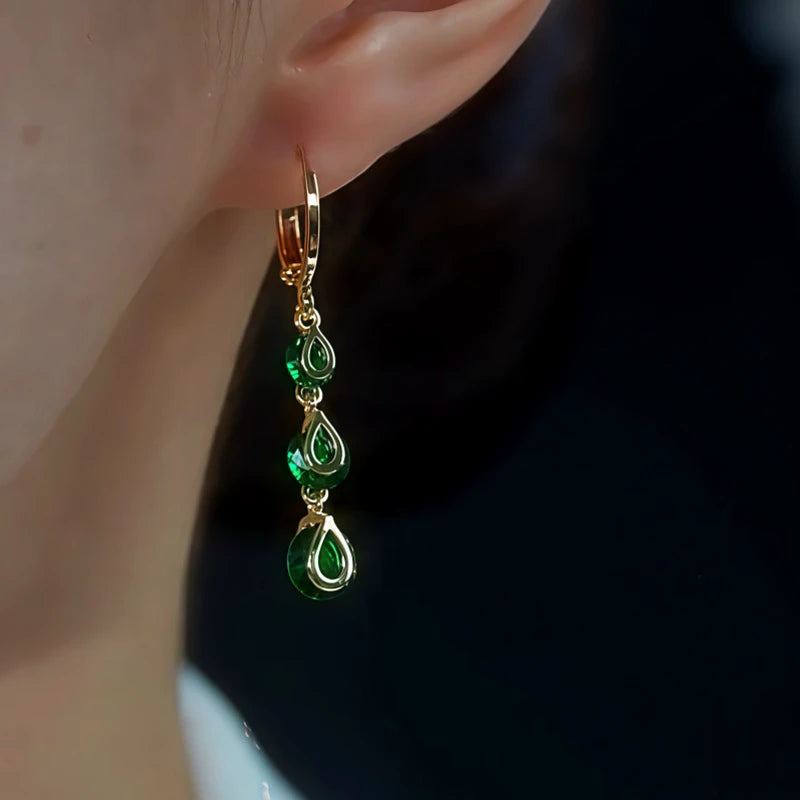 Side view of gold emerald green teardrop dangle hoop earring on ear