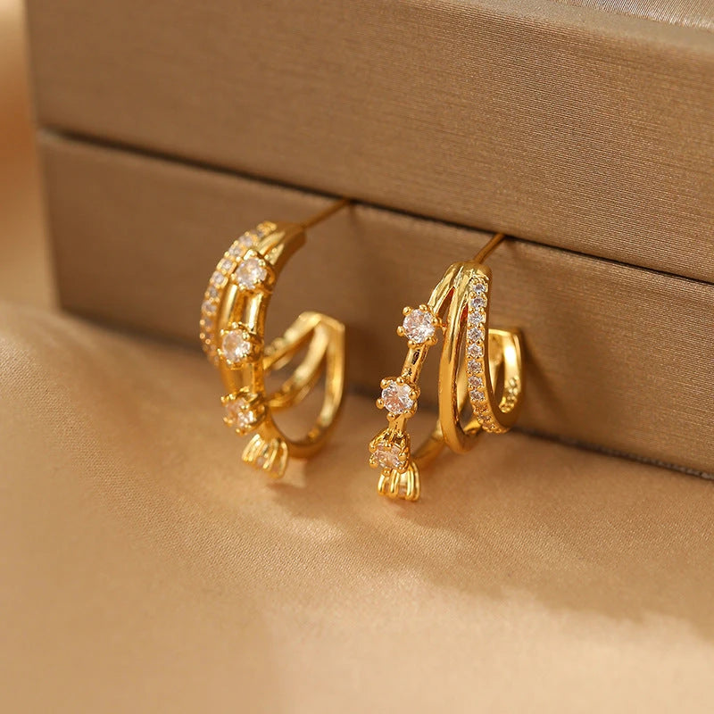 Close-up of gold triple-layer CZ hoop stud earrings on satin jewelry display