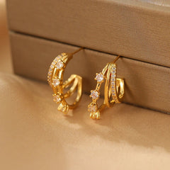Close-up of gold triple-layer CZ hoop stud earrings on satin jewelry display