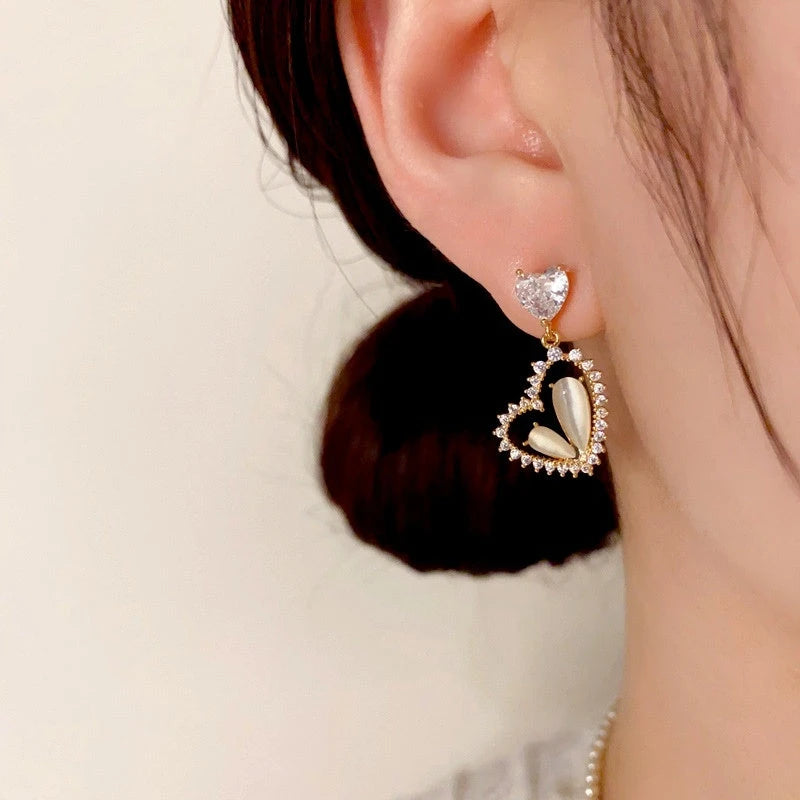 Model showcasing the dangle and style of the 14K Gold-Plated Zircon & Cat's Eye Stone Heart Earrings