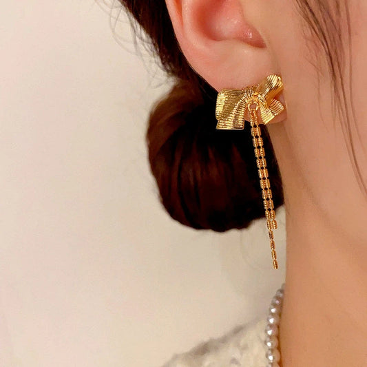 Model showcasing the dangle and style of the 14K Gold-plated Bow Tassel Earrings
