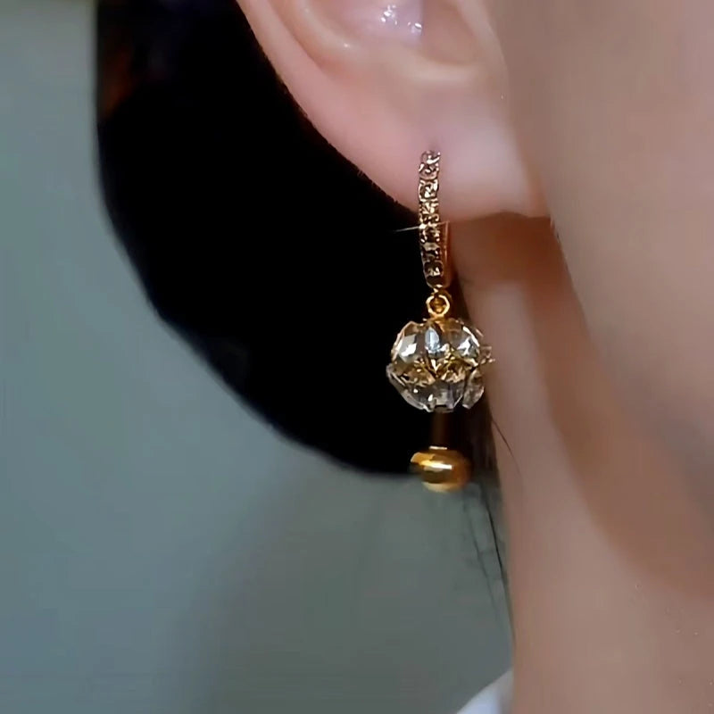 Model showcasing the dangle and style of the 14K Gold-plated Diamond Ball Earrings