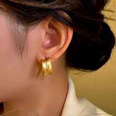 Model showcasing the dangle and style of the 14K Gold-plated Geometric Brushed Letter Earrings