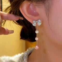 Model showcasing the dangle and style of the 14K Gold-plated Luxury Bow Pearl Tassel Earrings