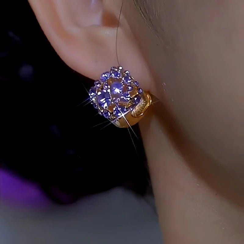 Matching sparkly purple rhinestone gold huggie earring on ear