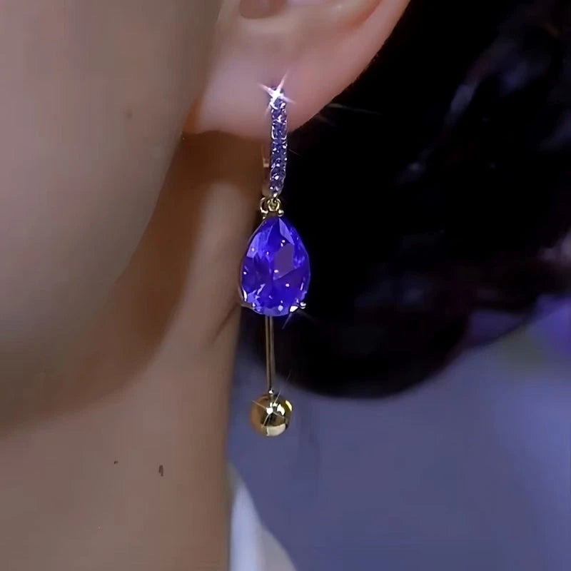 Sparkly purple teardrop crystal gold ball dangle hoop earring on ear side view