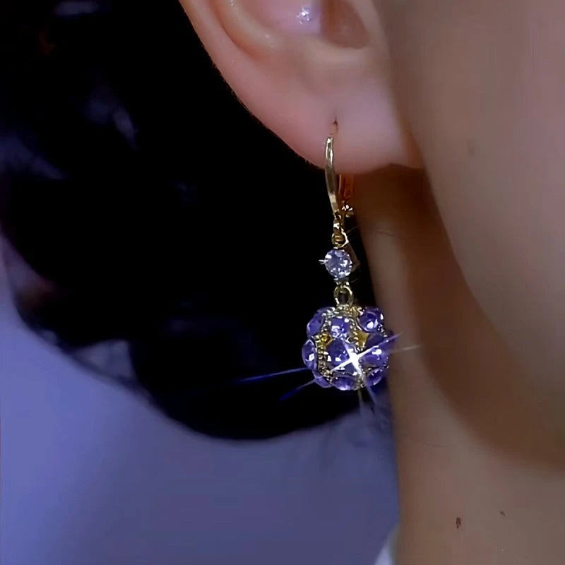 Sparkling purple crystal ball drop earring worn on woman's ear