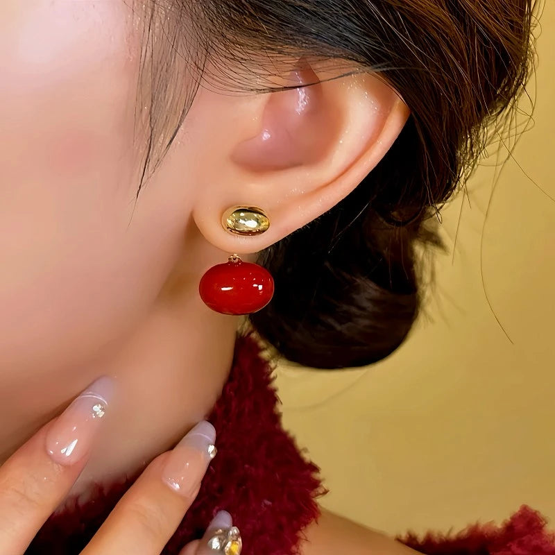Model showcasing the dangle and style of the 14K Gold-plated Red Enamel Bean Earrings
