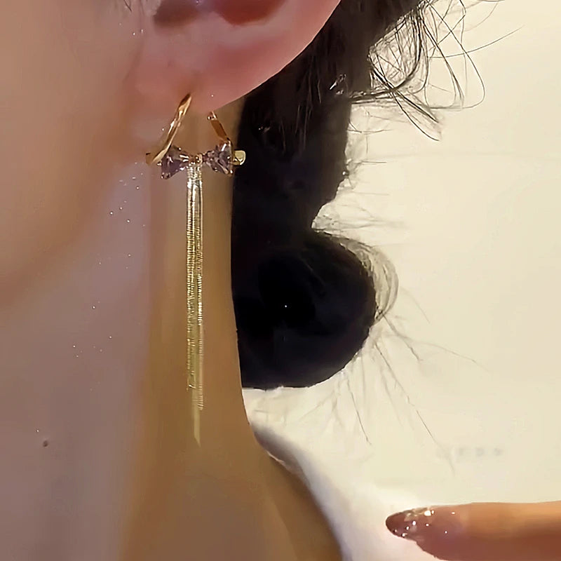 Model showcasing the dangle and style of the 14K Gold-plated Zircon Diamond Bow Tassel Earrings