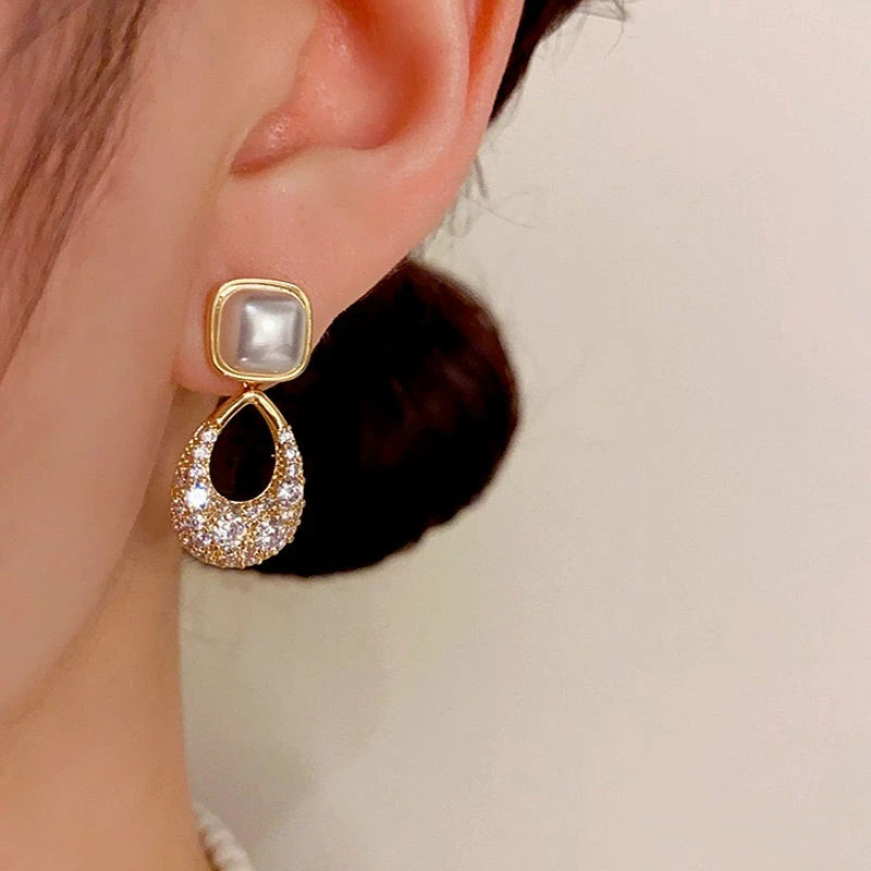 Model showcasing the dangle and style of the 14K Gold-plated Zircon Geometric Pearl Earrings
