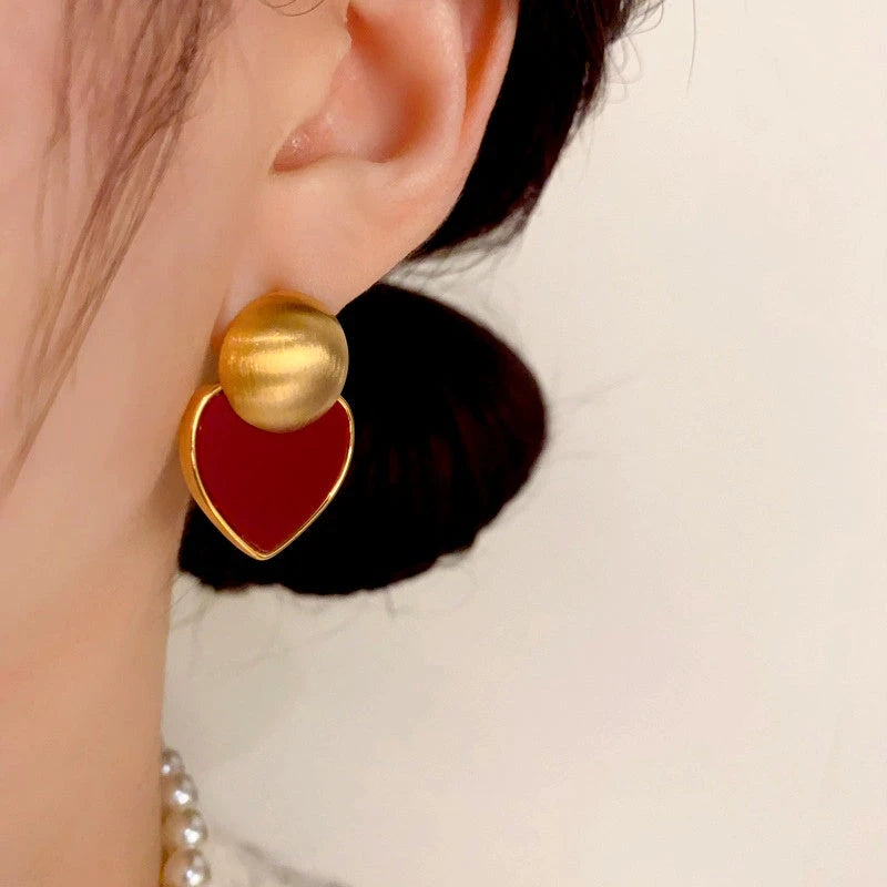 Model showcasing the dangle and style of the 14K Gold Plated Brushed Red Plate Love Heart Earrings