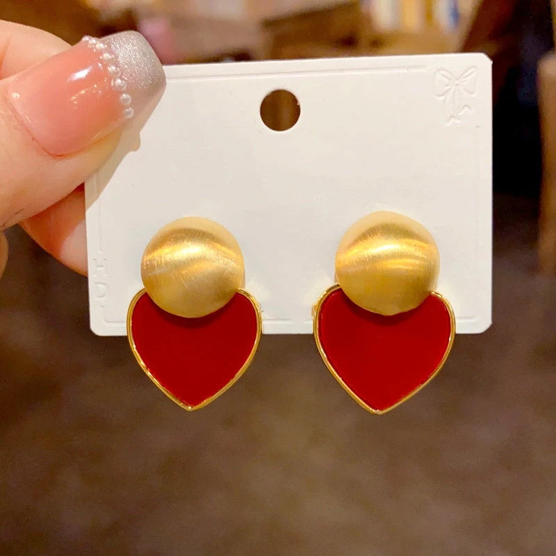 Angled view of the 14K Gold Plated Brushed Red Plate Love Heart Earrings