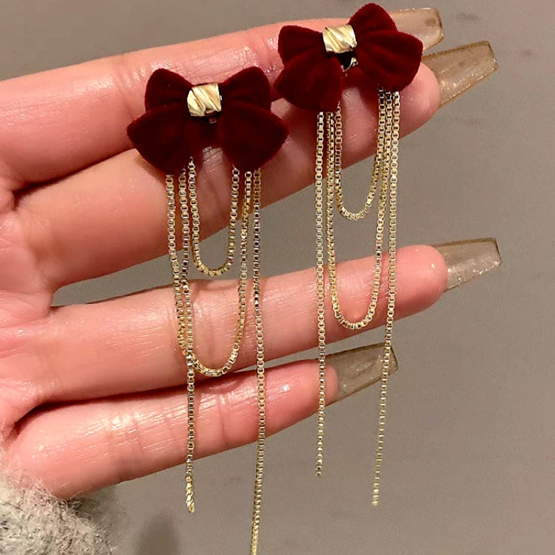 Model showcasing the dangle and style of the 14K Gold Plated Christmas Bow Tassel Earrings