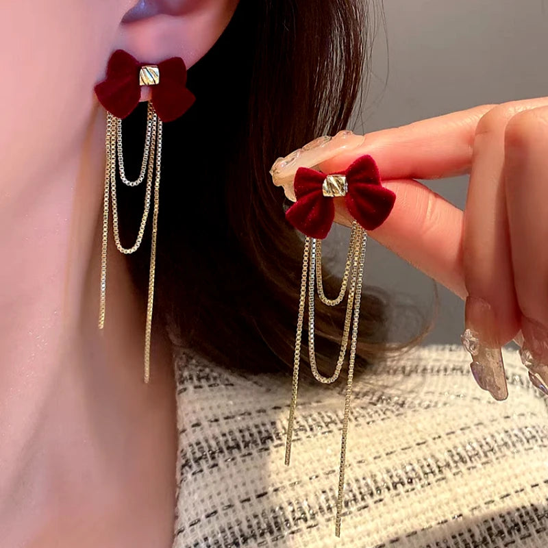 Angled view of the 14K Gold Plated Christmas Bow Tassel Earrings