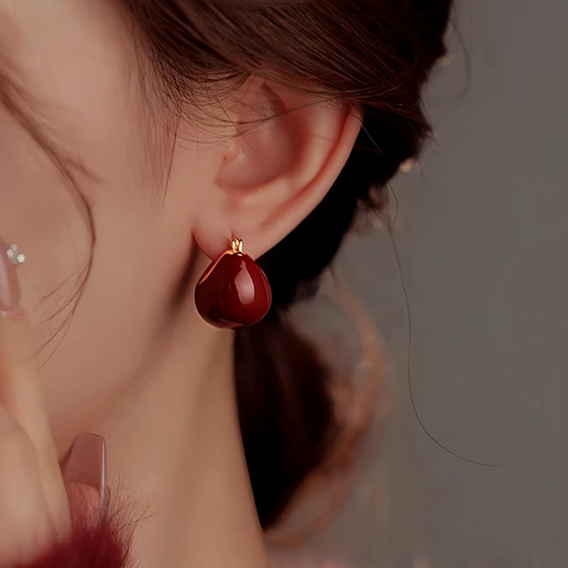 Model showcasing the dangle and style of the 14K Gold Plated Glaze Wine Red Basket Earrings