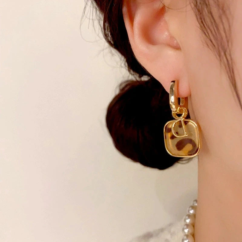 Model showcasing the dangle and style of the 14K Gold Plated Leopard Print D Letter Earrings