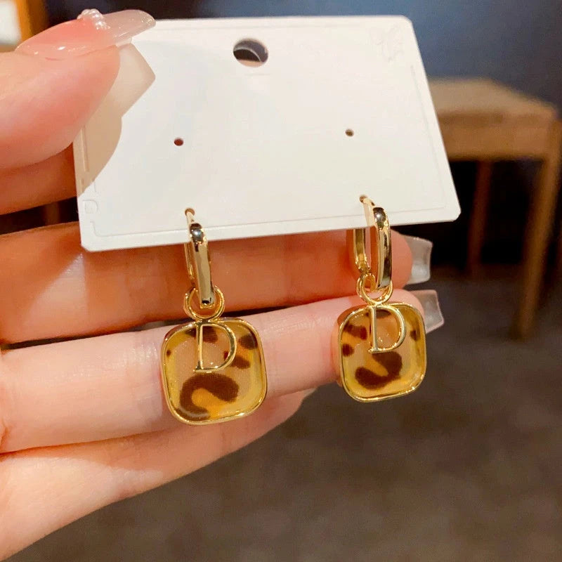 Angled view of the 14K Gold Plated Leopard Print D Letter Earrings