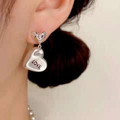Model showcasing the dangle and style of the 14K Gold Plated Love Letter Heart Earrings