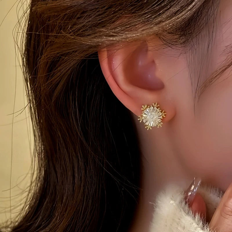 Model showcasing the dangle and style of the 14K Gold Plated Rotating Snowflake Stud Earrings