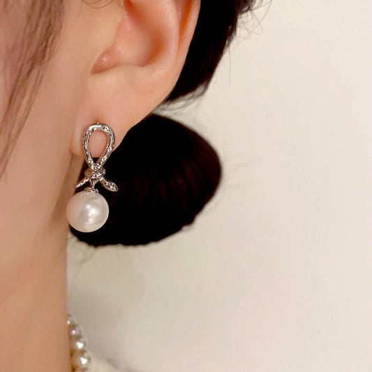 Model showcasing the dangle and style of the 14K Gold Plated Snake Knotted Pearl Earrings