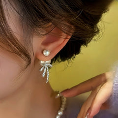 Model showcasing the dangle and style of the 14K Gold Plated Zircon Bow Pearl Earrings