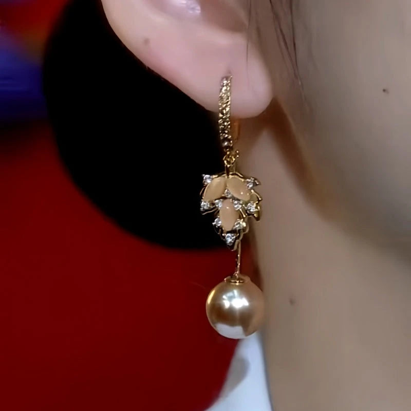 Model showcasing the dangle and style of the 14K Gold Plated Zircon Cat's Eye Stone Maple Leaf Brown Pearl Earrings