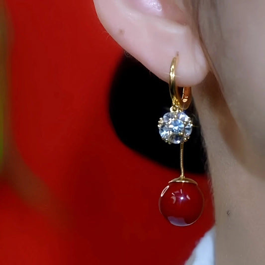 Model showcasing the dangle and style of the 14K Gold Plated Zircon Red Bead Earrings